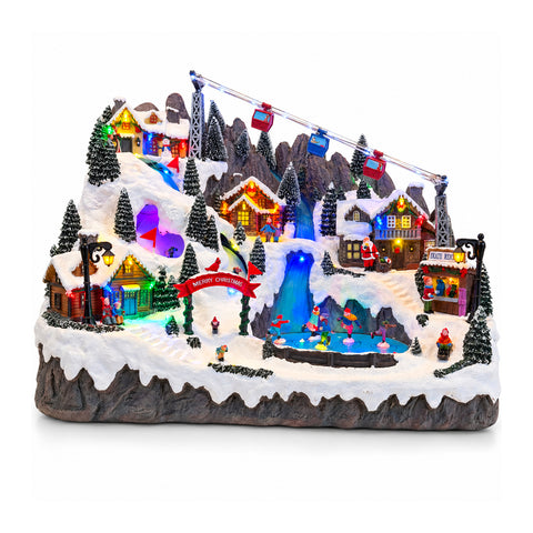 Pueblo navideño luminoso con pistas de esquí y patinaje en movimiento, luces LED y música – 56x37x42 cm