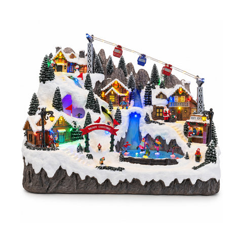 Pueblo navideño luminoso con pistas de esquí y patinaje en movimiento, luces LED y música – 56x37x42 cm